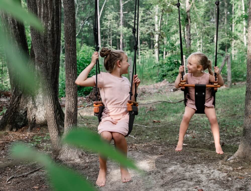 Active play outdoors - 2 children playing on Solvej Scandi wooden swings from Oskar's Wooden Ark in Australia