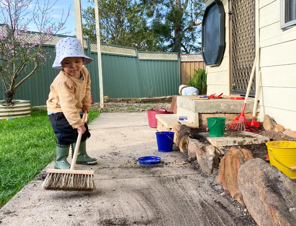 Boy sweeping with Gluckskafer children's broom from Oskar's Wooden Ark in Australia