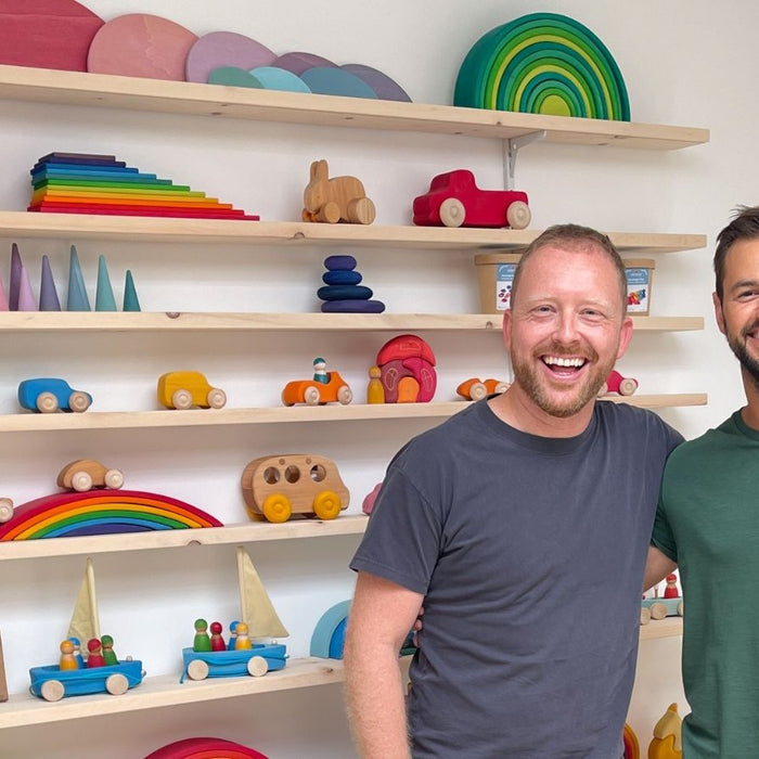 Simon with Marco from Grimm's Wooden Toys in front of a wall of colourful wooden Grimm's children's toys and shelves.