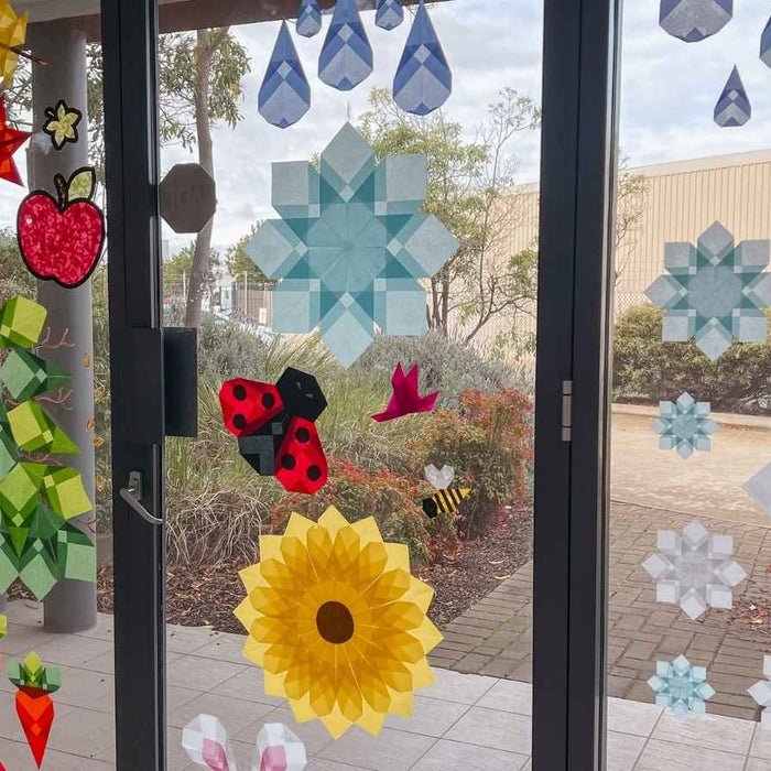 Paper window art display on a window, with sunlight shining through.