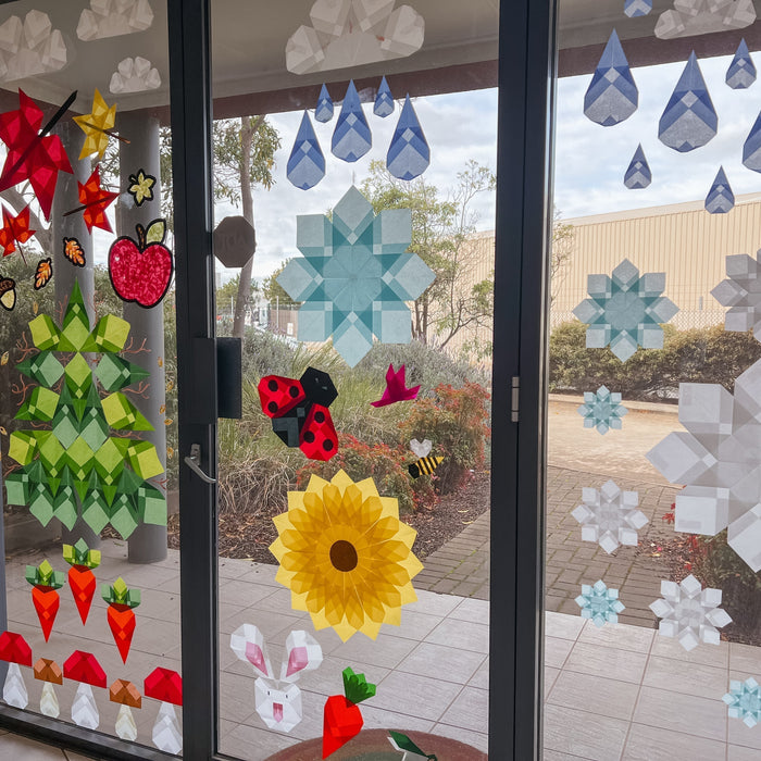 Paper window art display on a window, with sunlight shining through.