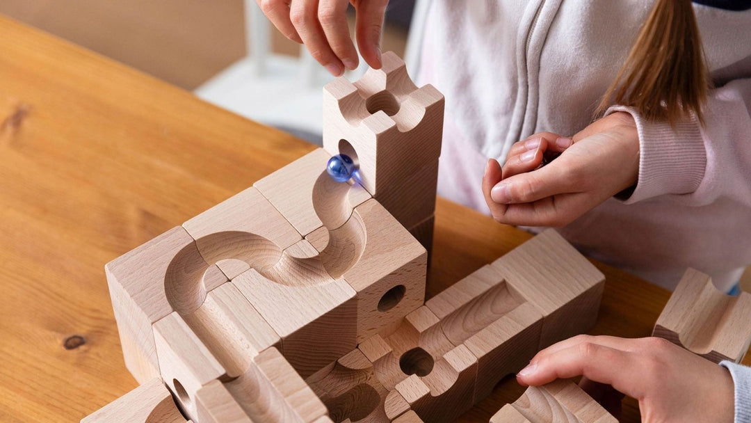 Child placing a glass marble at the top of a CUBORO wooden marble run