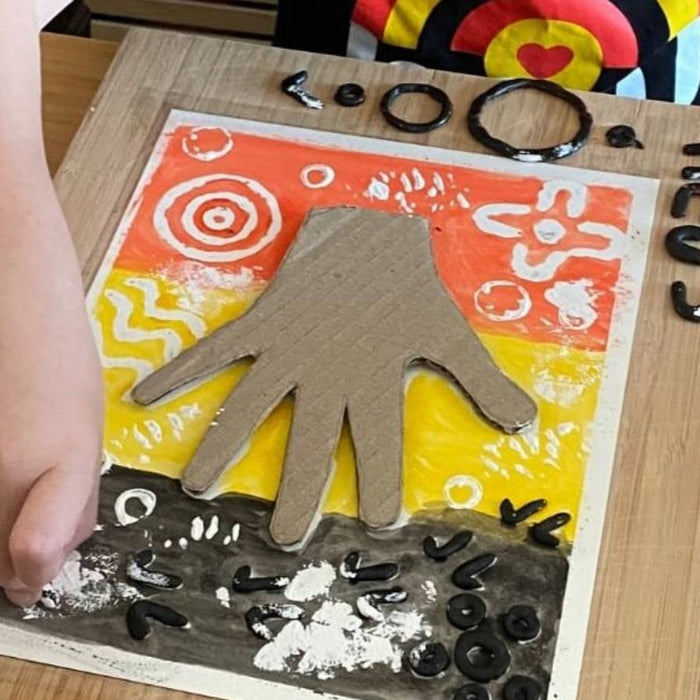 Child painting over beeswax symbols with Aboriginal flag colours for NAIDOC Week