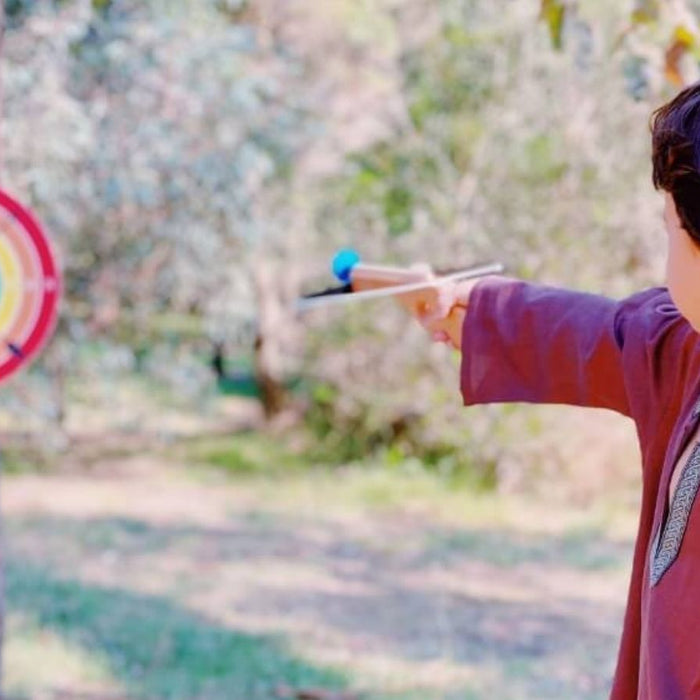 Child playing with VAH handmade wooden crossbow for imaginative role play