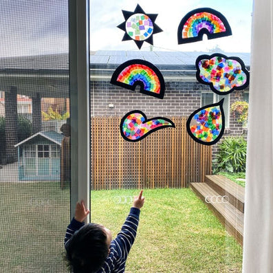 Child admiring handmade paper sun catchers using transparent waxed kite paper at Oskar's Wooden Ark in Australia