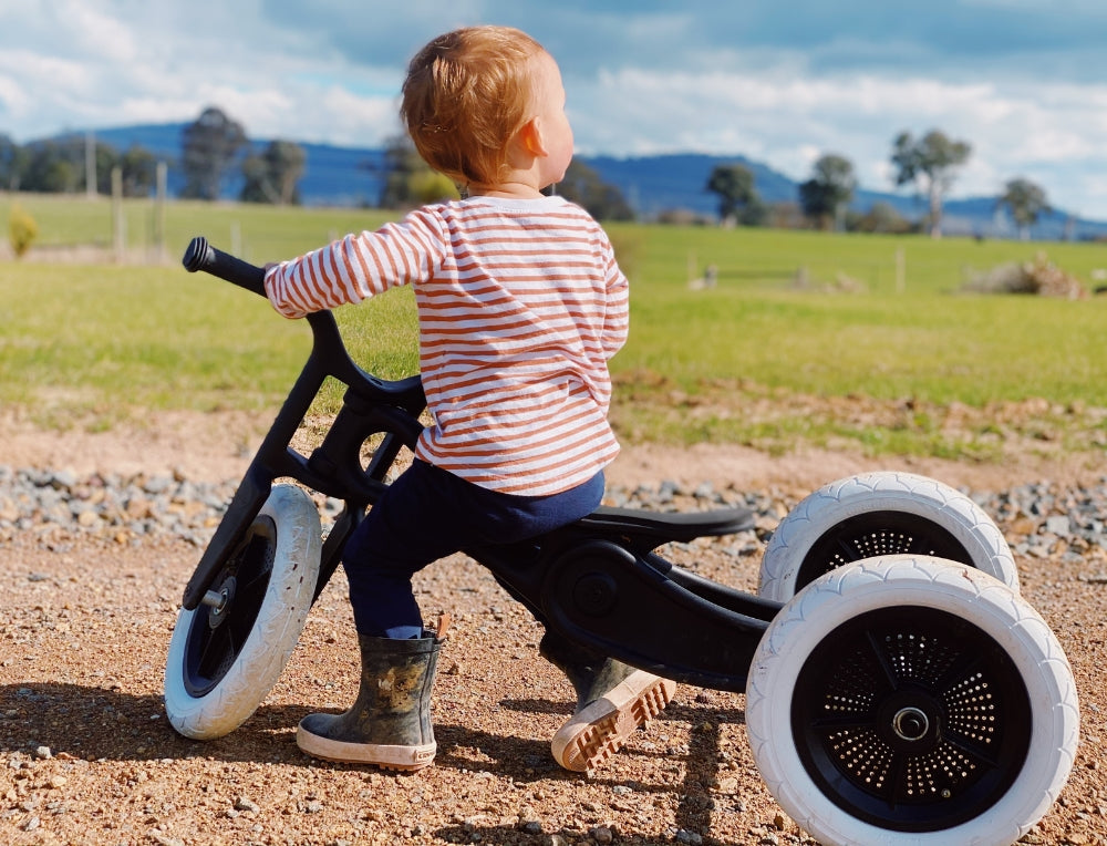 Child riding a Wishbone Recycled Plastic Balance Bike, Trike combo made from recycled materials at Oskar's Wooden Ark in Australia