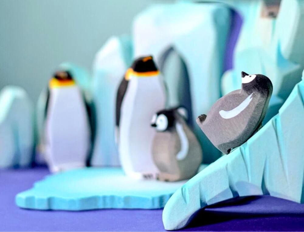 Penguins sliding down an ice berg - small world play scene with Bumbu wooden animal figurines from Bumbu Wooden Toy, available in Australia from Oskar's Wooden Ark