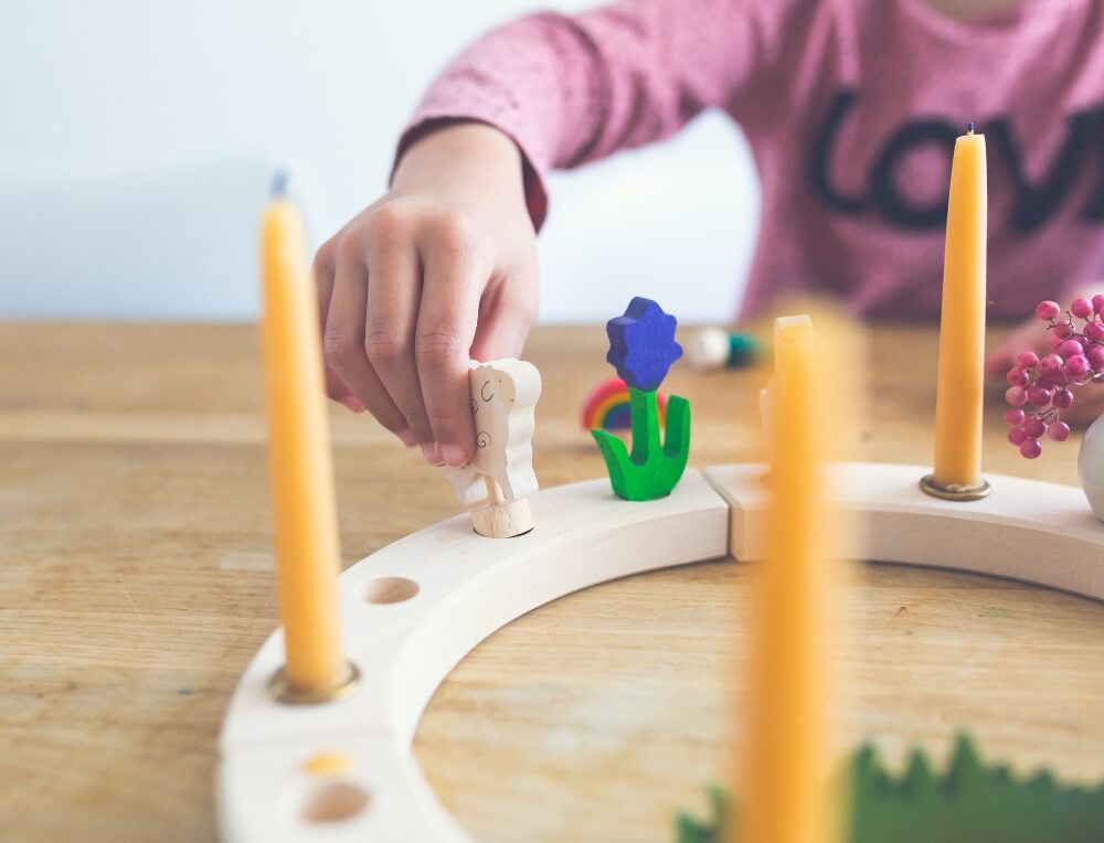 Decorating a Grimm's Waldorf Celebration Ring with wooden figures and beeswax candles, available in Australia from Oskar's Wooden Ark