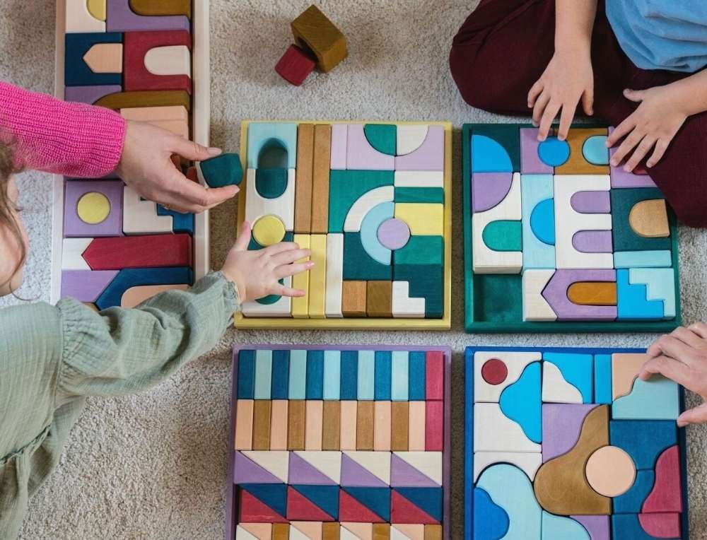 Children playing with new 2026 Grimm's Wooden Toys Tiny Art Collection building sets on a carpeted floor