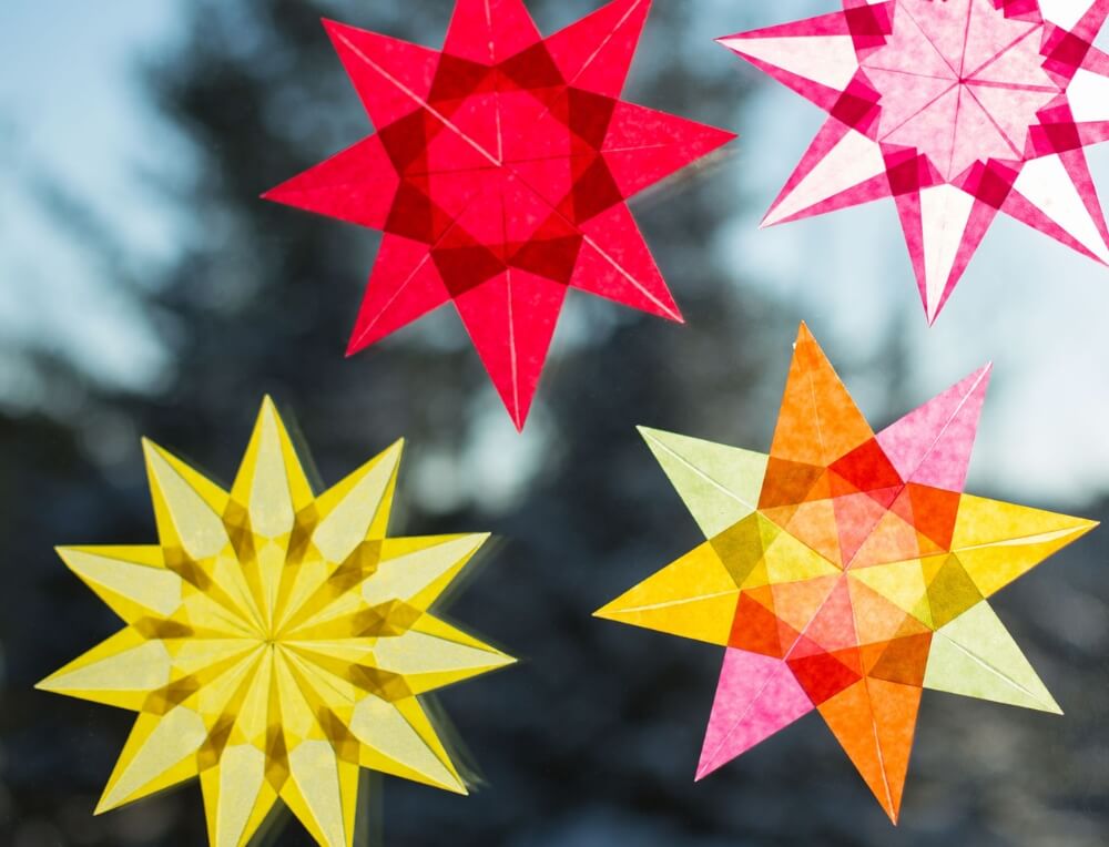 Colourful star-shaped paper decorations against a blurred natural background - Art and craft materials on sale at Oskar's Wooden Ark
