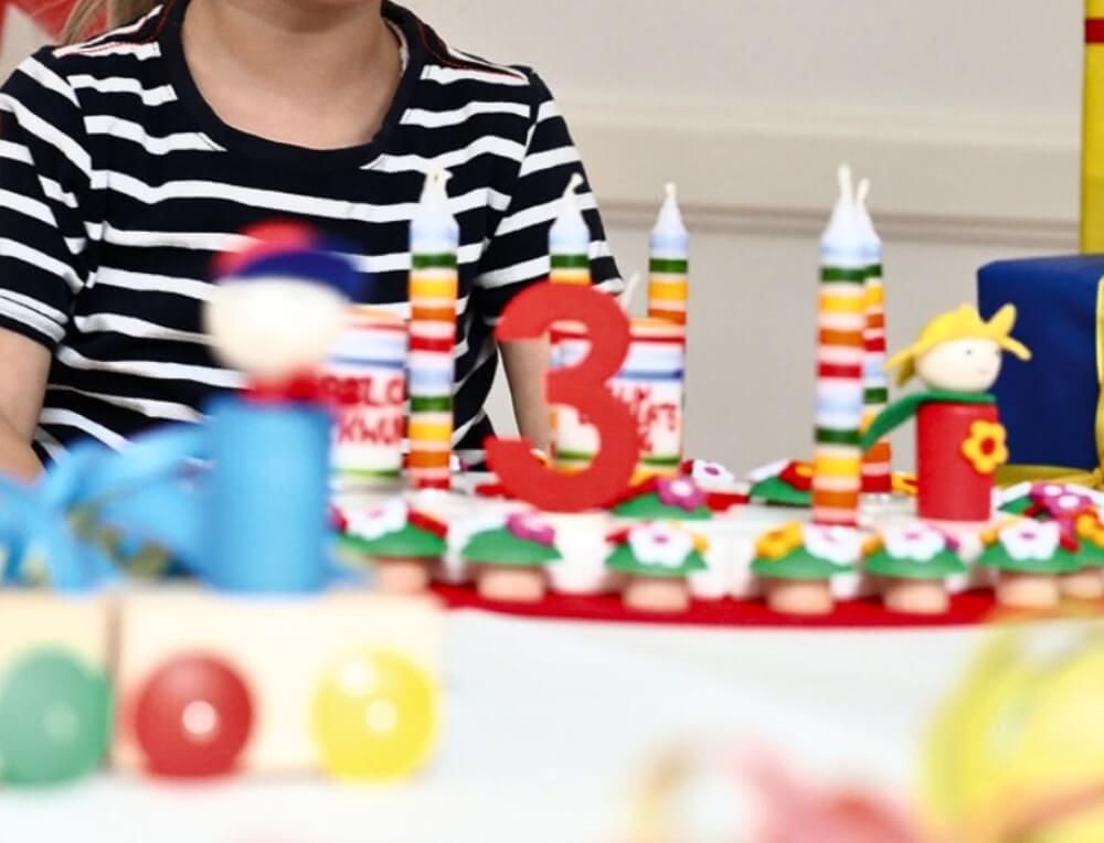 Child sitting at a Birthday table with a celebration ring and candles - Celebration and Home products on sale at Oskar's Wooden Ark
