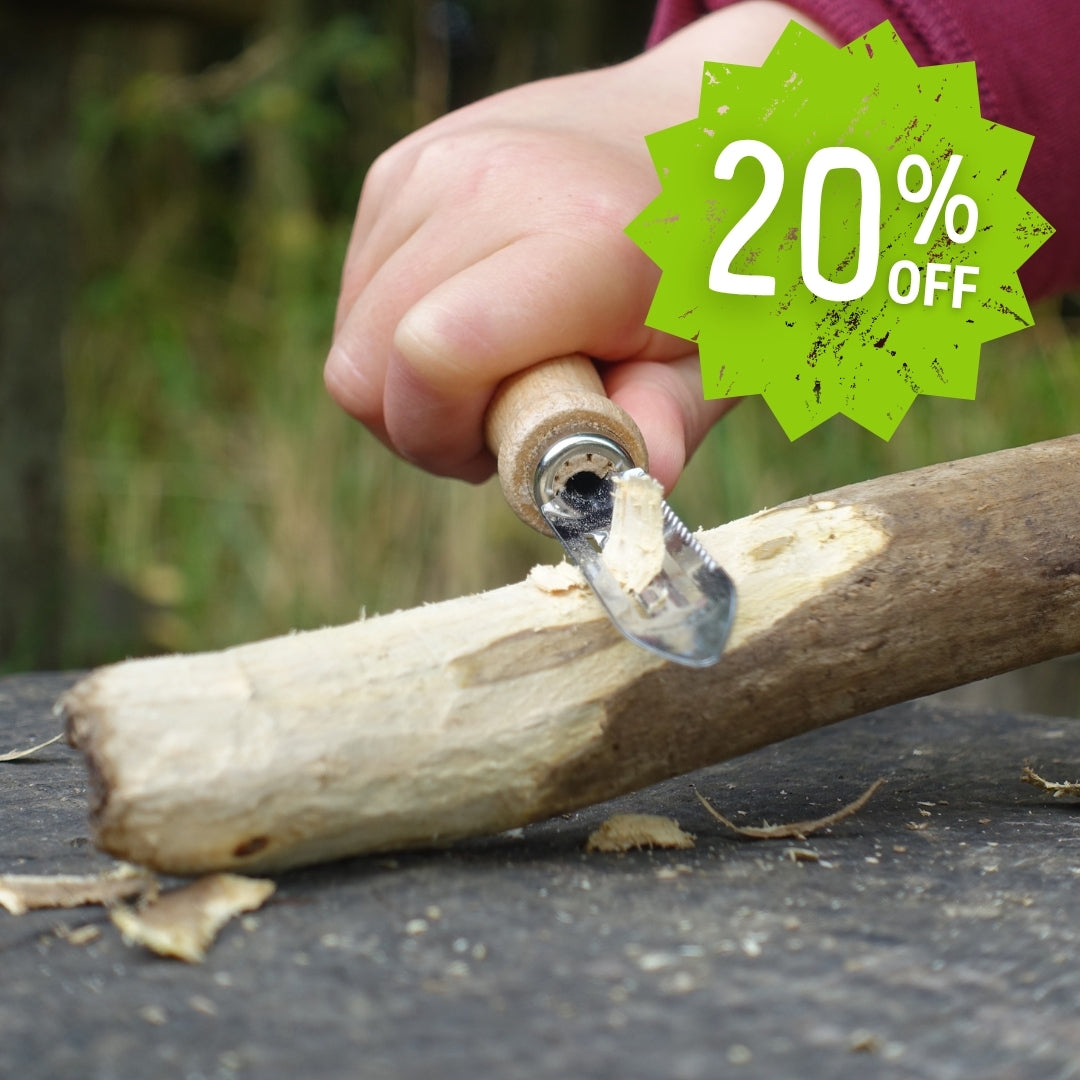 Child's hand using a Kids at Work whittling knife with a 20% off discount label in the corner.