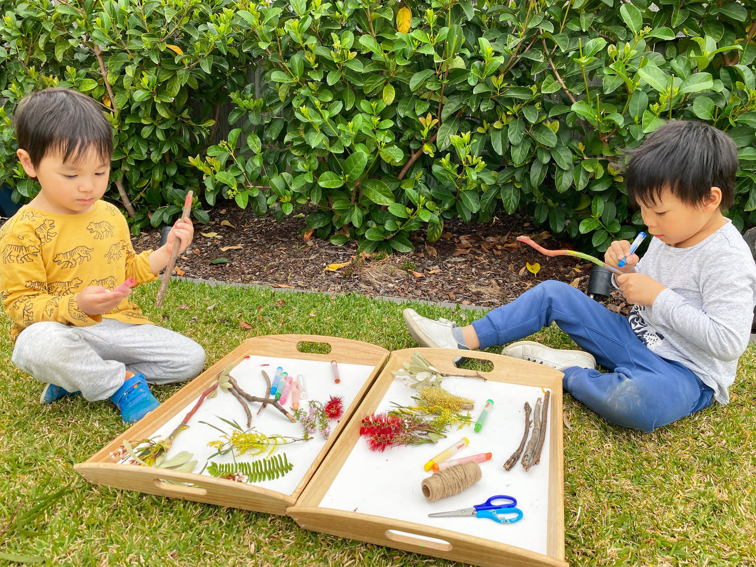 Children collecting sticks and flowers for nature wand craft activity with Kitpas Crayons and Scissors