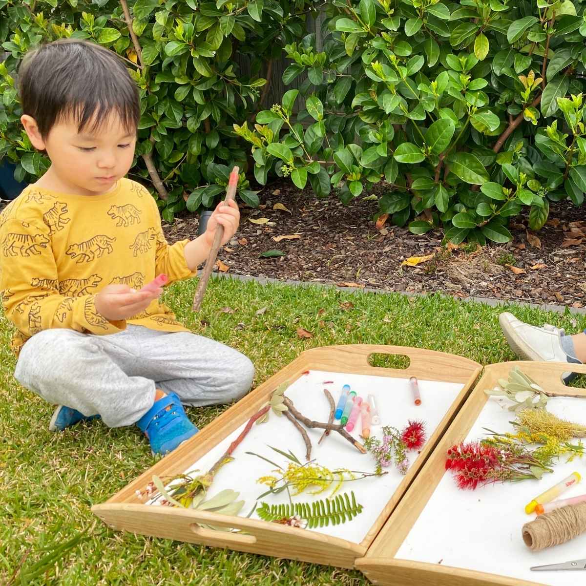 Children collecting sticks and flowers for nature wand craft activity with Kitpas Crayons and Scissors