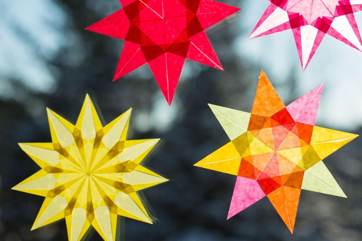 Colorful star-shaped paper decorations against a blurred natural background