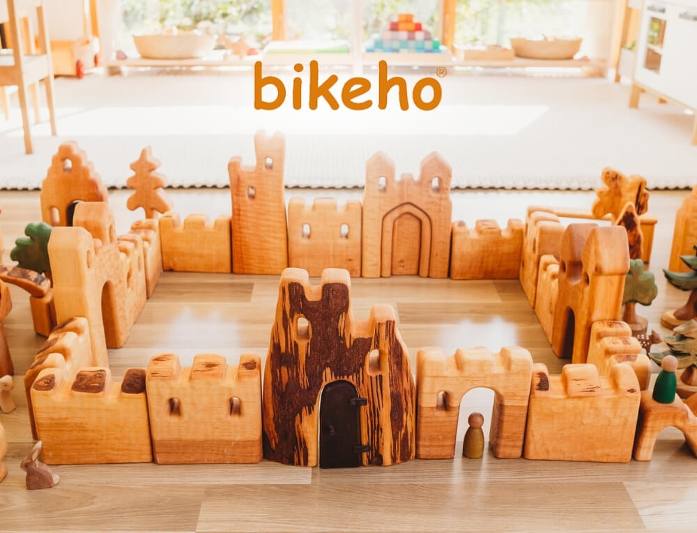 Bikeho lifestyle image with logo, featuring a wooden castle play set made from multiple natural wood blocks and walls – Oskar's Wooden Ark