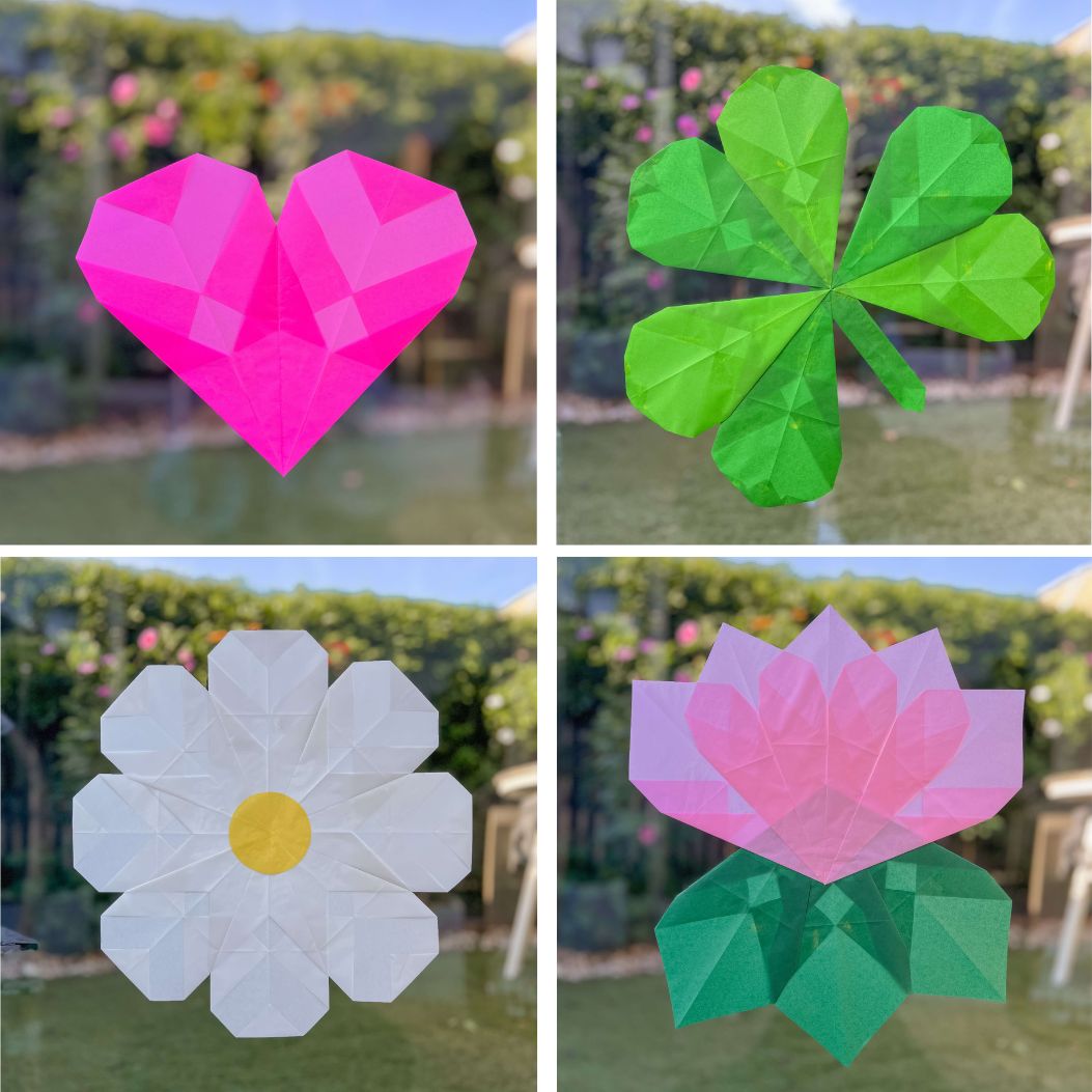 Four simple paper window crafts arranged on a window pane.