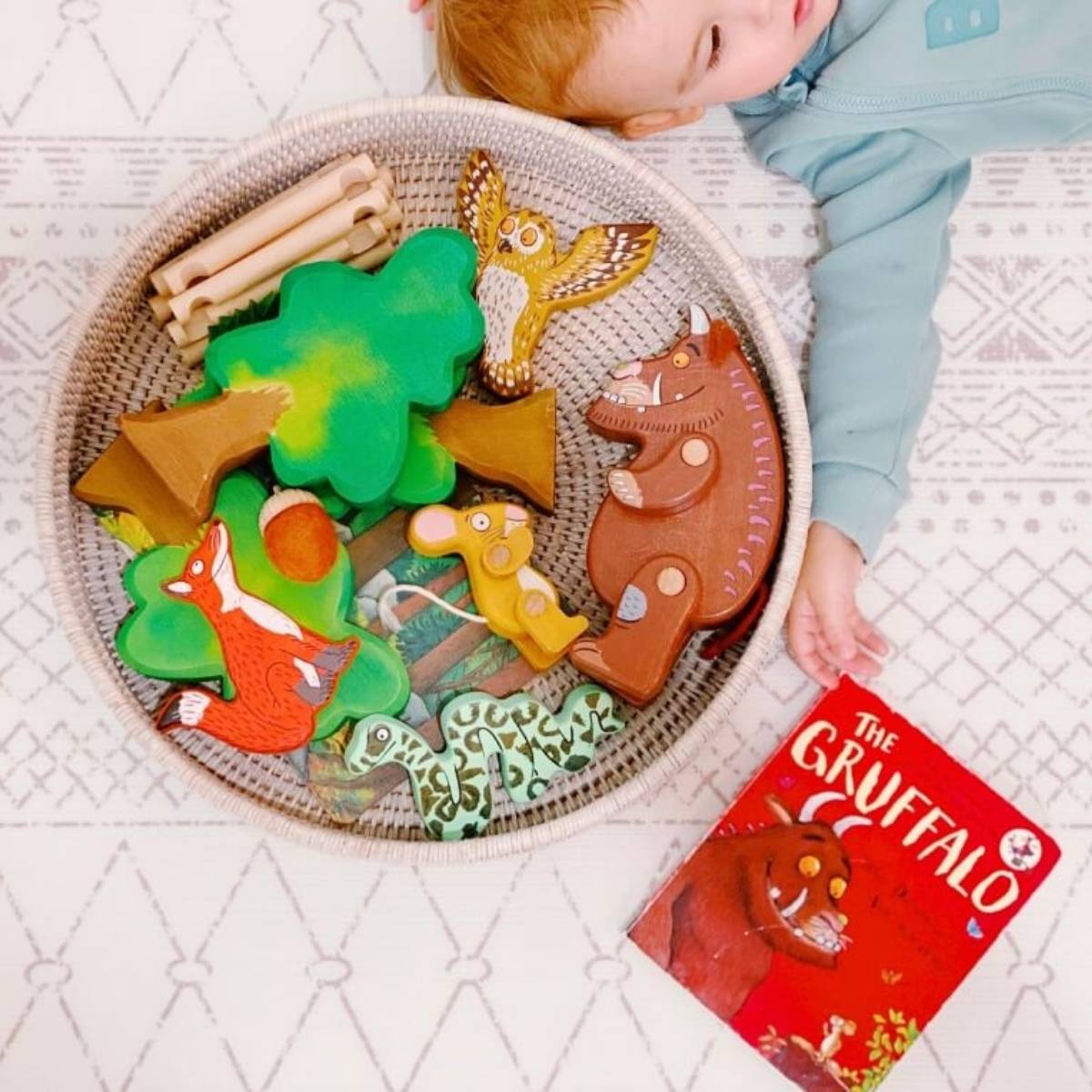 Baby exploring Gruffalo wooden toys during bookish play.