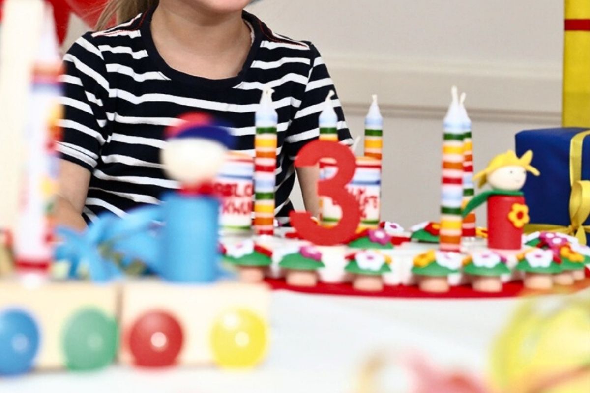 Child standing behind a birthday celebration ring with Ahrens candles and decorations.