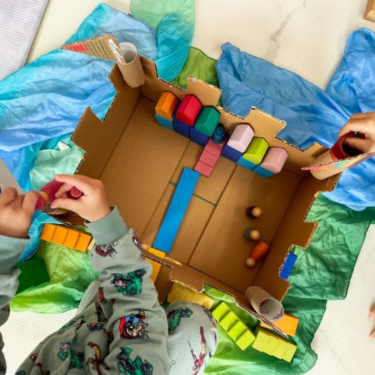 Children playing with finished cardboard castle in small world play