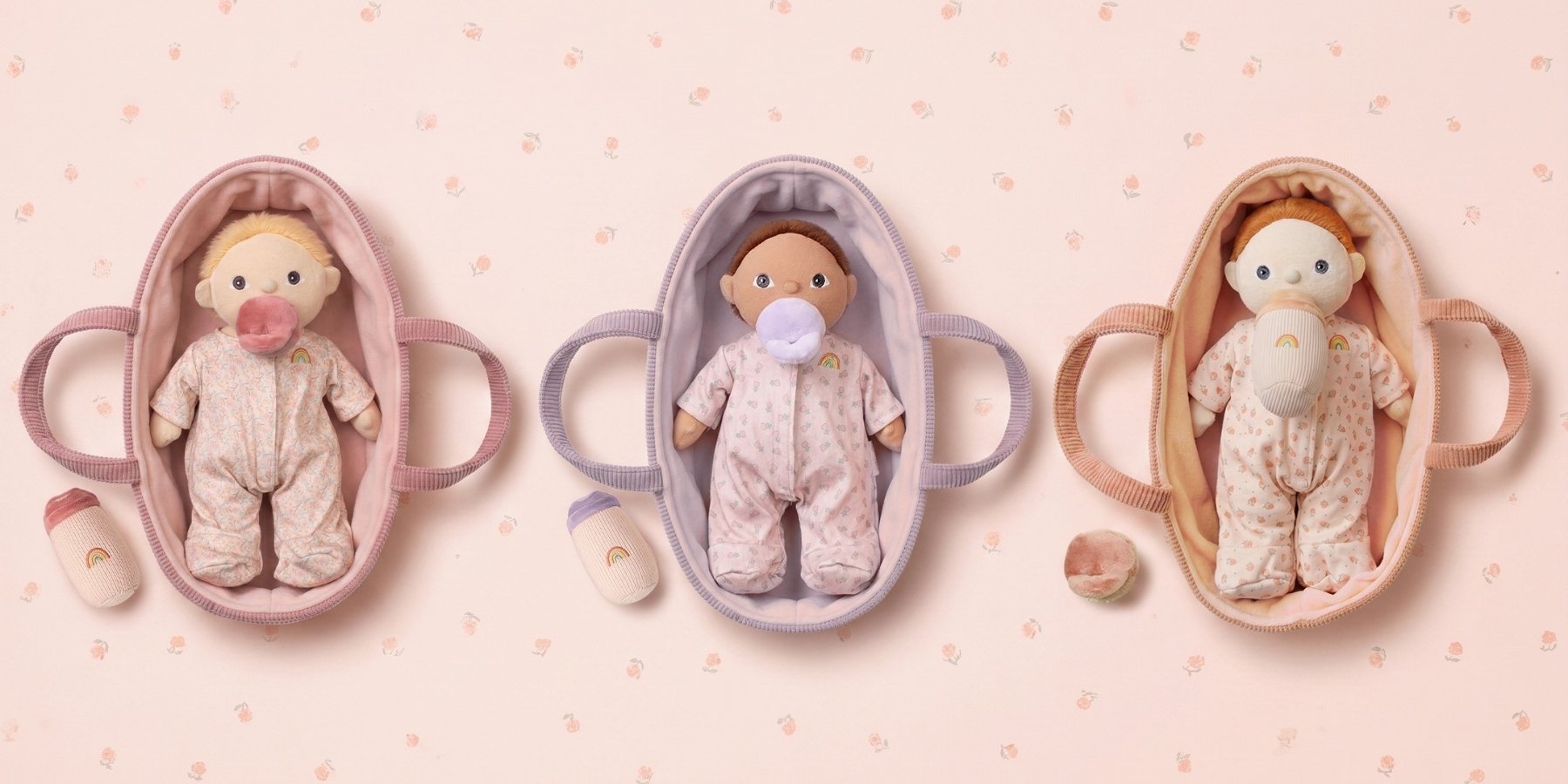 Three Dinky Binky Dinkum Dolls in cradles on a pink background