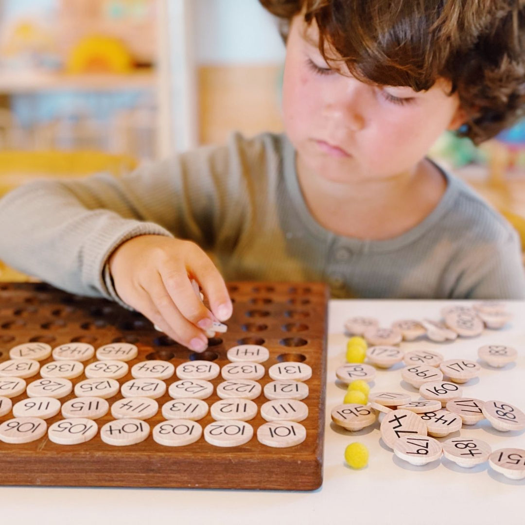 Child practicing counting with a From Jennifer wooden hundred board - Oskar's Wooden Ark