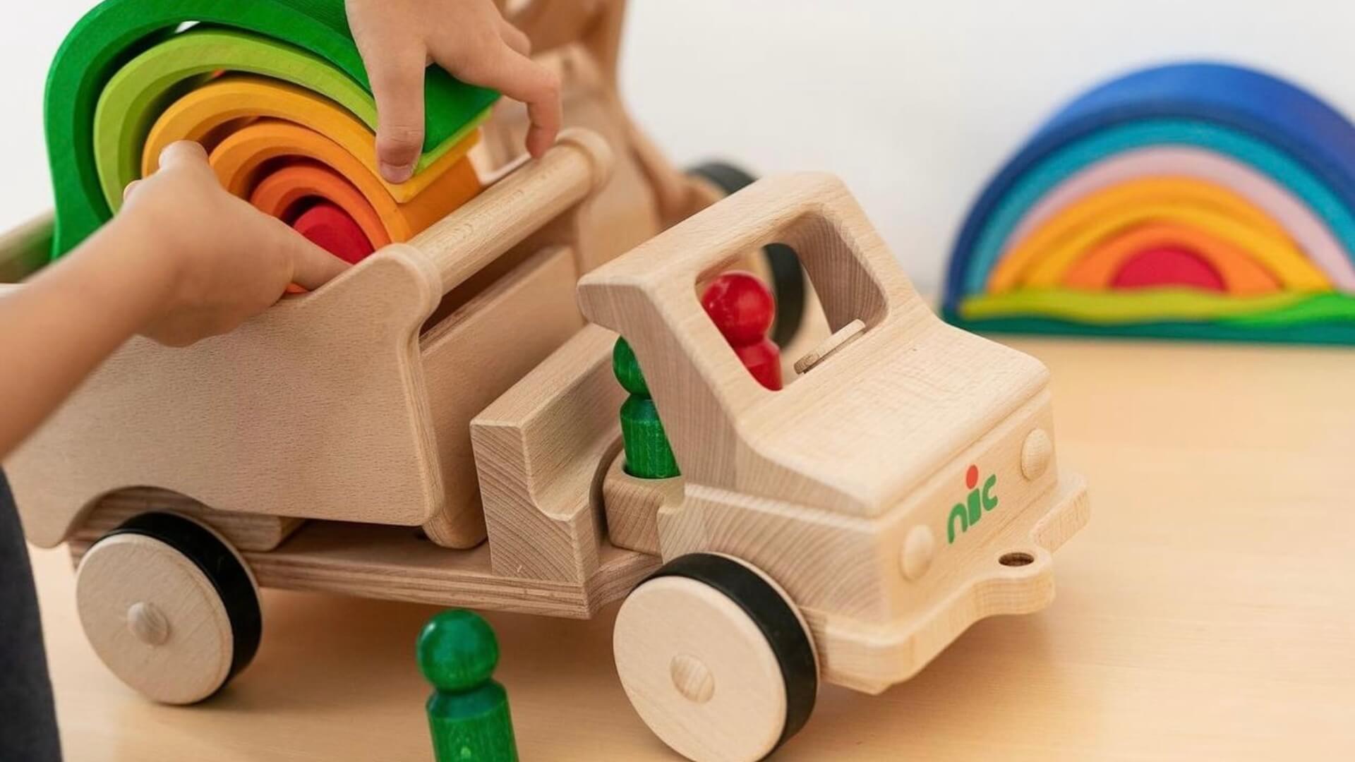 Wooden nic toy truck with colourful Gluckskafer blocks and a rainbow in the background