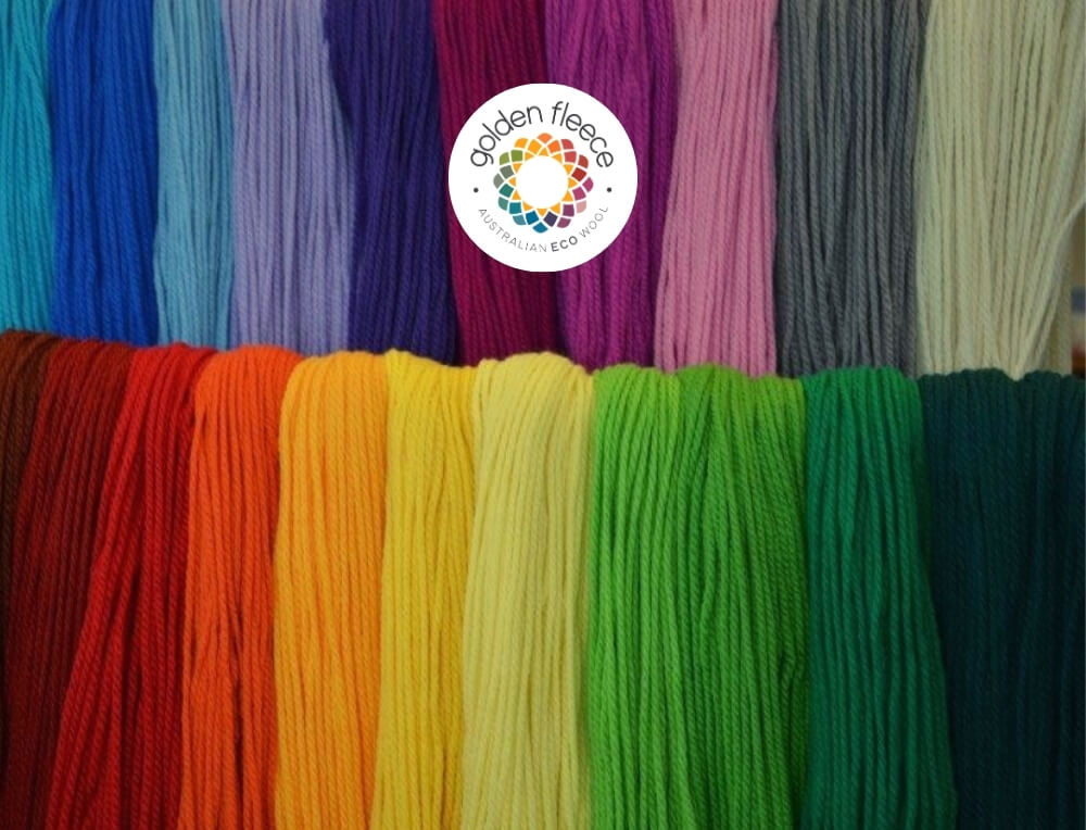 Golden Fleece Australian eco wool image with logo, featuring a close-up display of multiple skeins of yarn arranged in vertical rows, showing a wide range of colours – Oskar's Wooden Ark