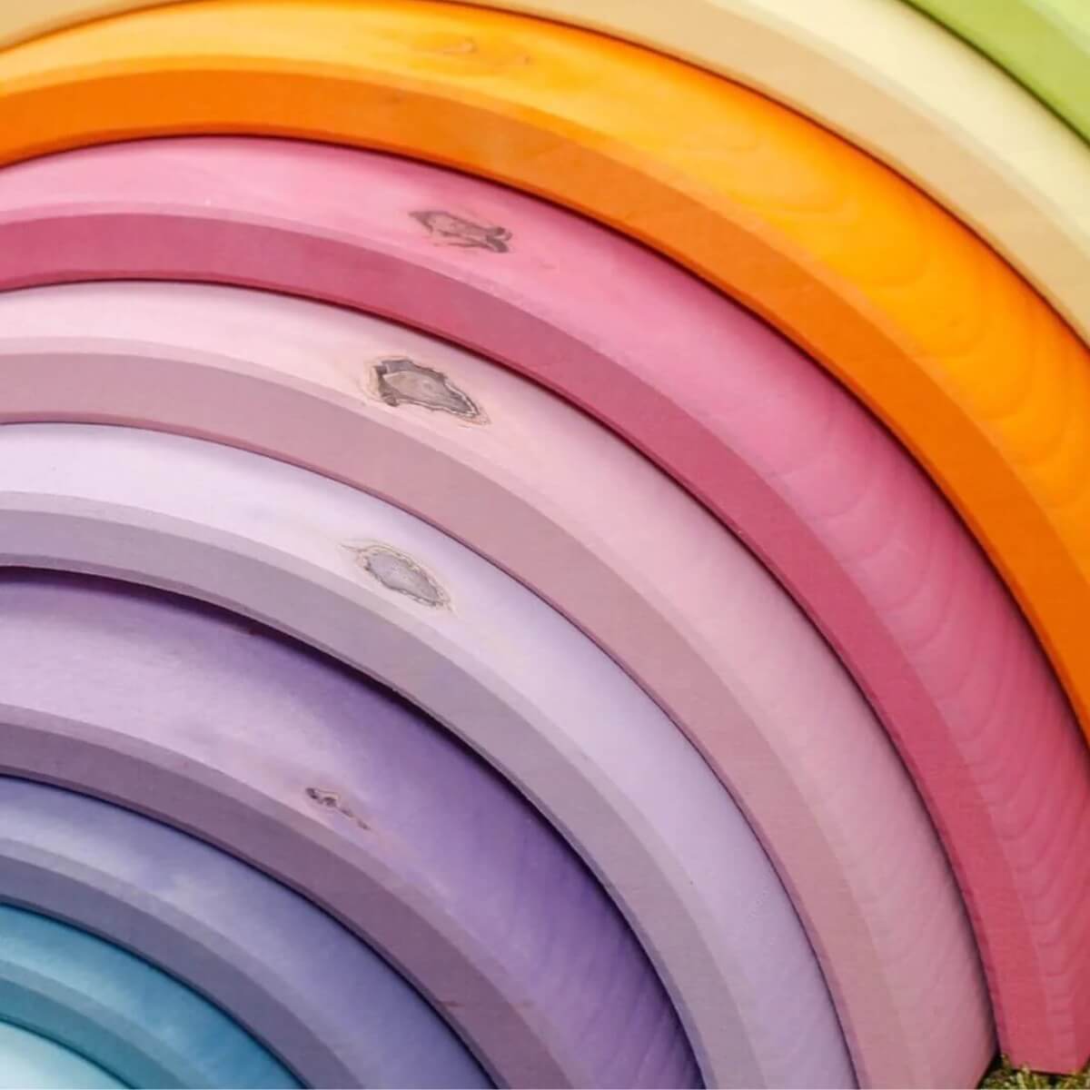 A close-up of a Grimm's rainbow arches in pastel and bright tones, showing natural wood markings.