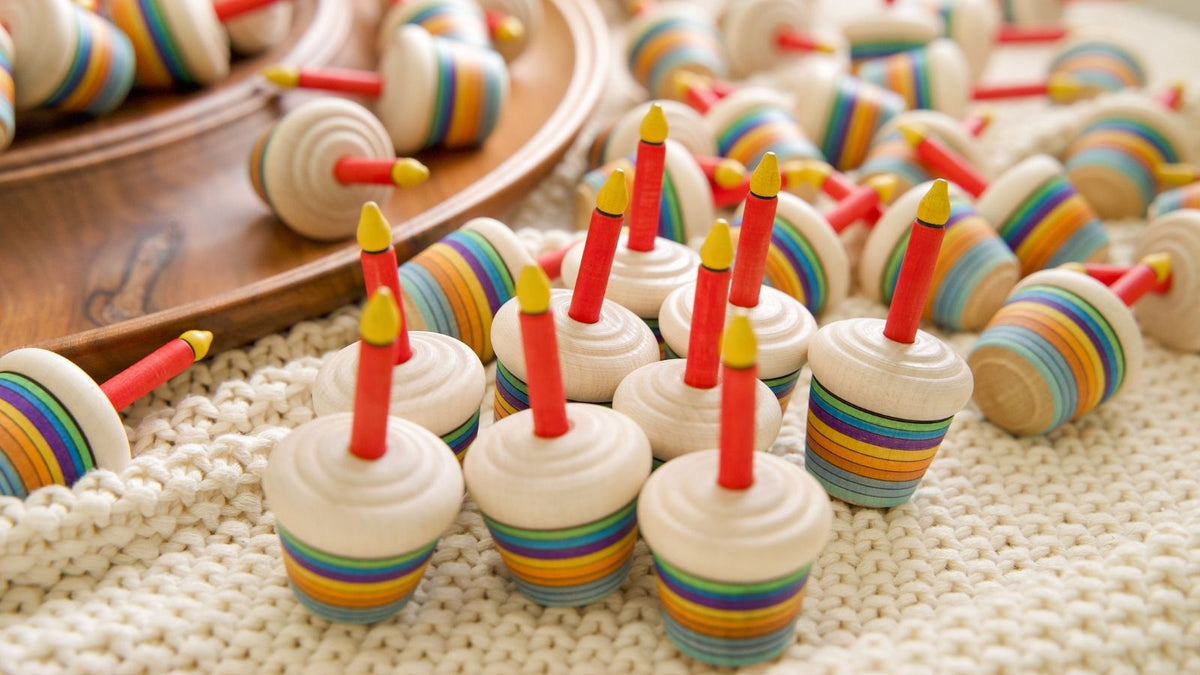 Mader handcrafted cupcake spinning tops on a blanket and a wooden rondell