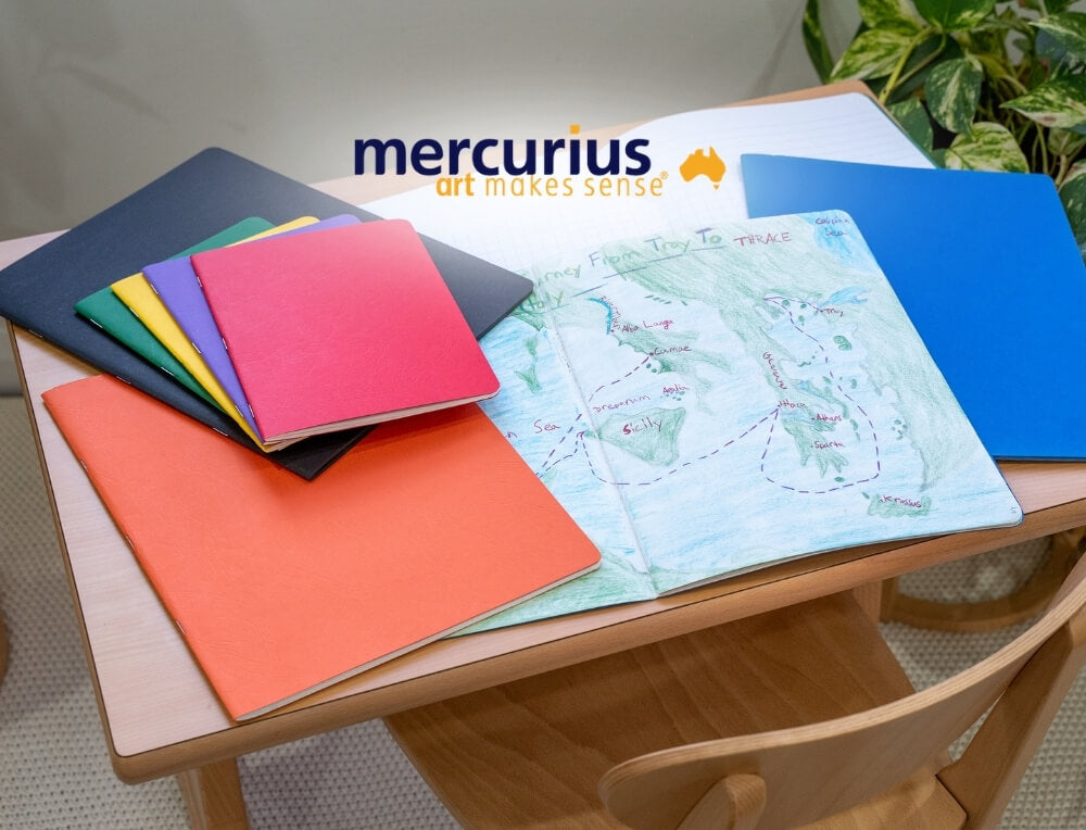 Mercurius Australia lifestyle image with logo, featuring a collection of colourful art and school lesson books on a wooden table – Oskar's Wooden Ark