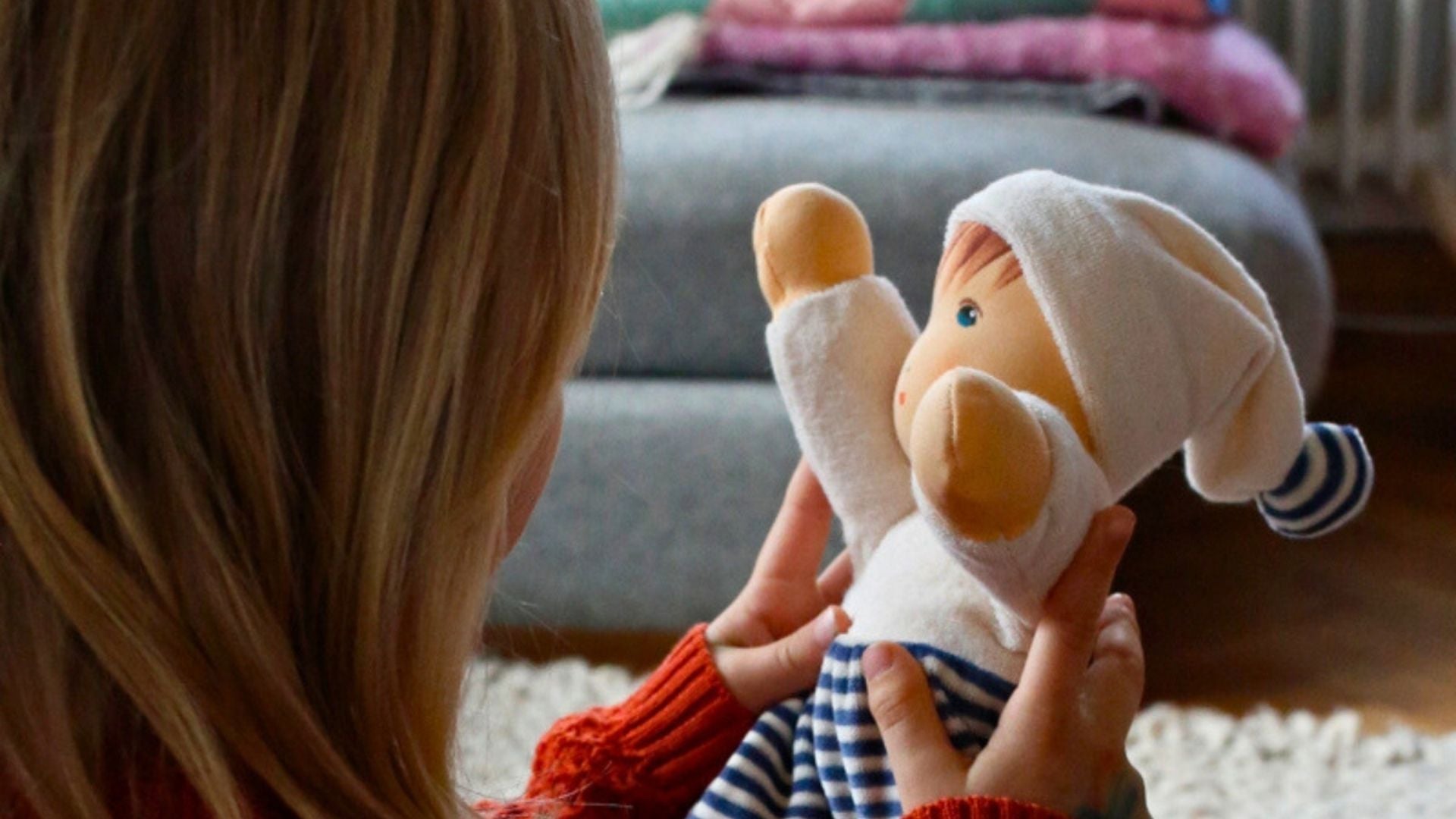 Child holding a soft handcrafted Nanchen Natur doll in a cozy indoor setting