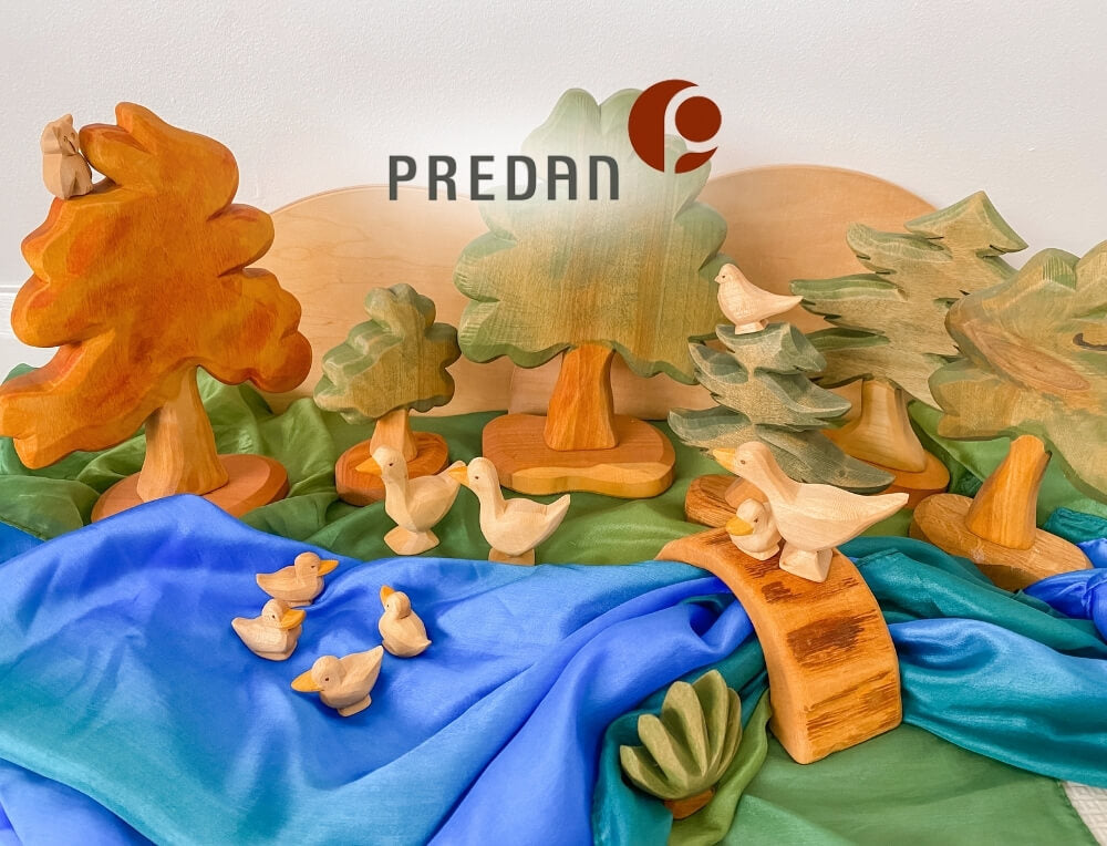 Predan Wooden Toys lifestyle image with logo, featuring a set of handcrafted wooden duck figures and nature-themed toys on a blue playsilk – Oskar's Wooden Ark