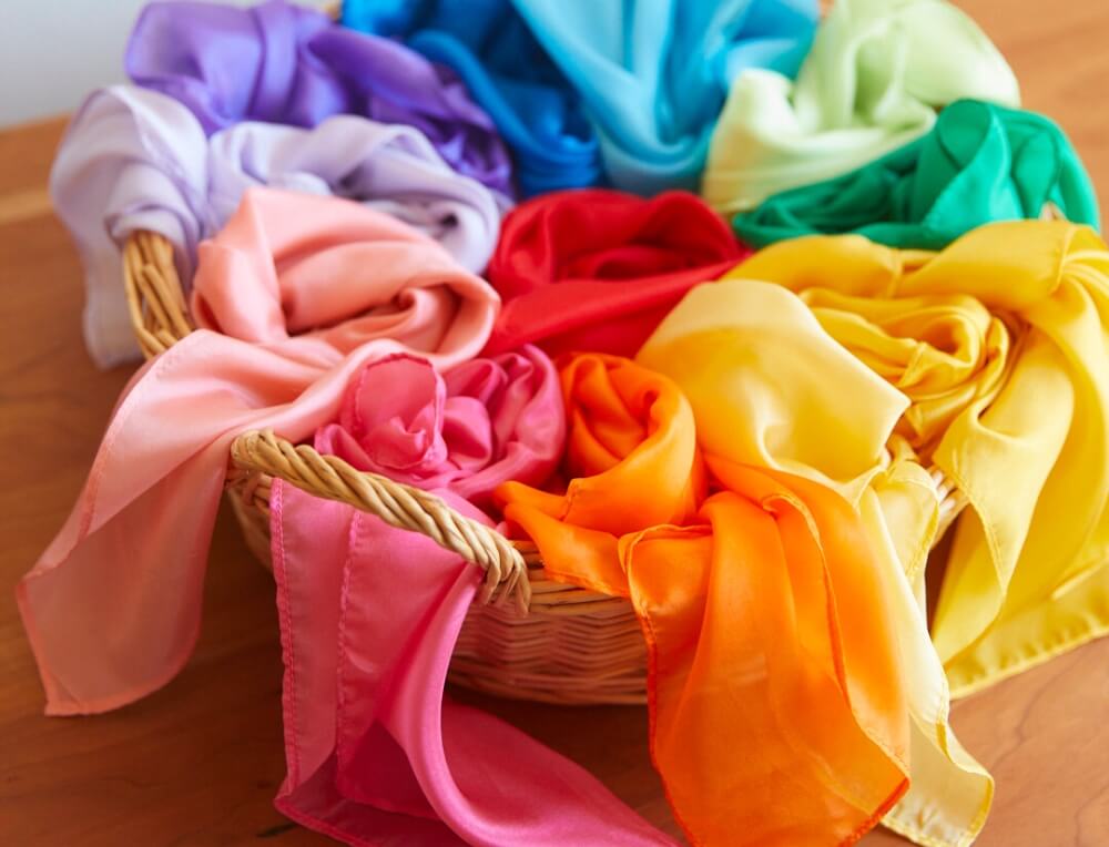 Basket of colourful Sarah's Silks Play Silks in rainbow colours to invite creative play from Oskar's Wooden Ark in Australia