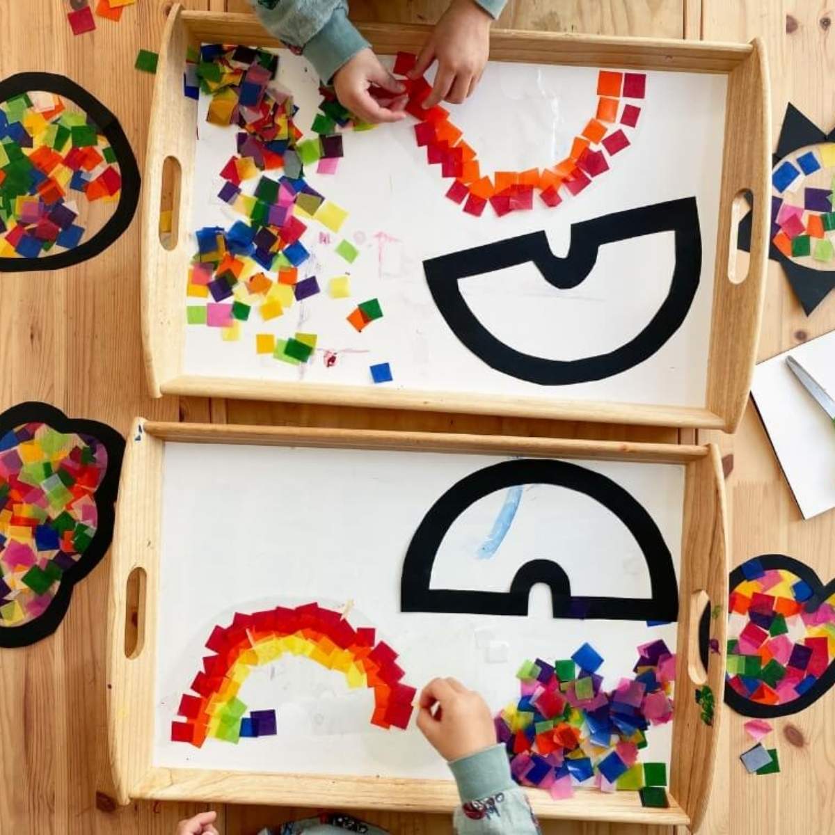 A child making a sun catcher with colourful waxed kite paper squares on sticky contact shapes.
