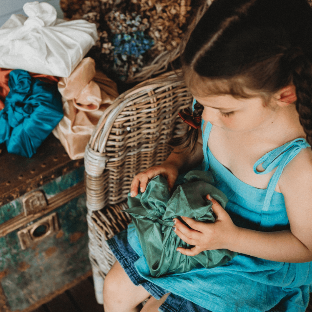 Child wrapping a gift using fabric scraps, tea towels and household materials