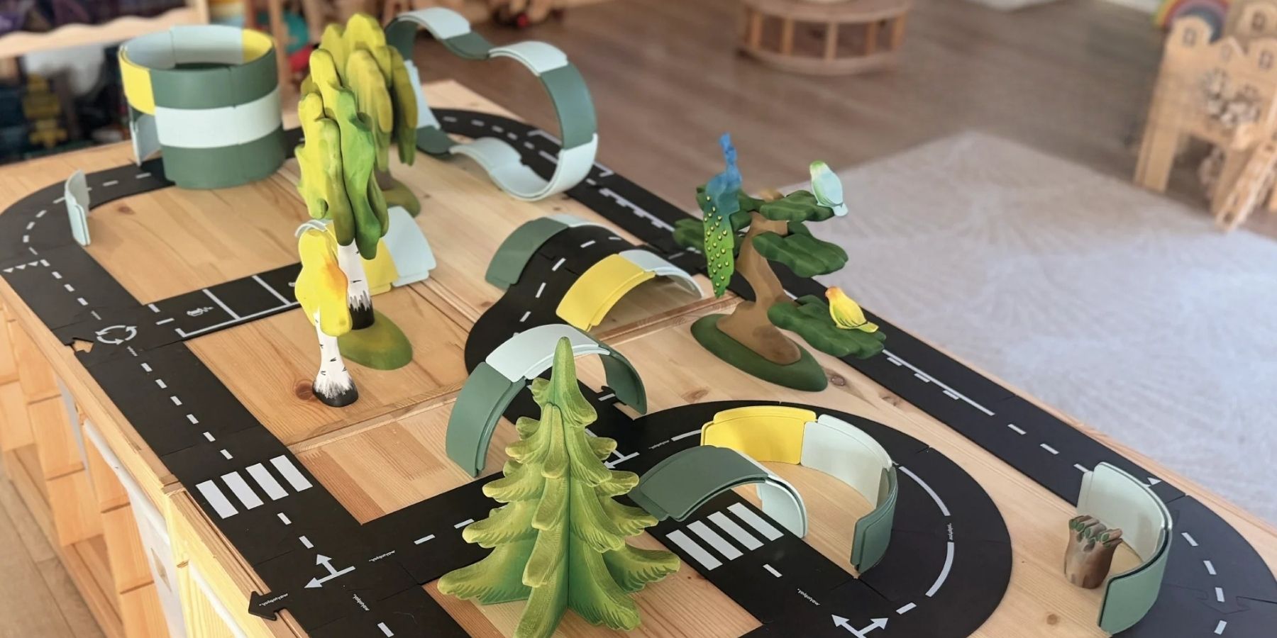 Way to Play flexible road toy on a play table with Bumbu wooden trees and figures and tunnels and bridges created using Waytoplay Curves