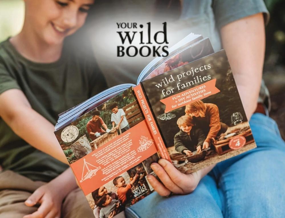 Your Wild Books lifestyle image with logo, featuring a child and parent reading together outdoors – Oskar's Wooden Ark