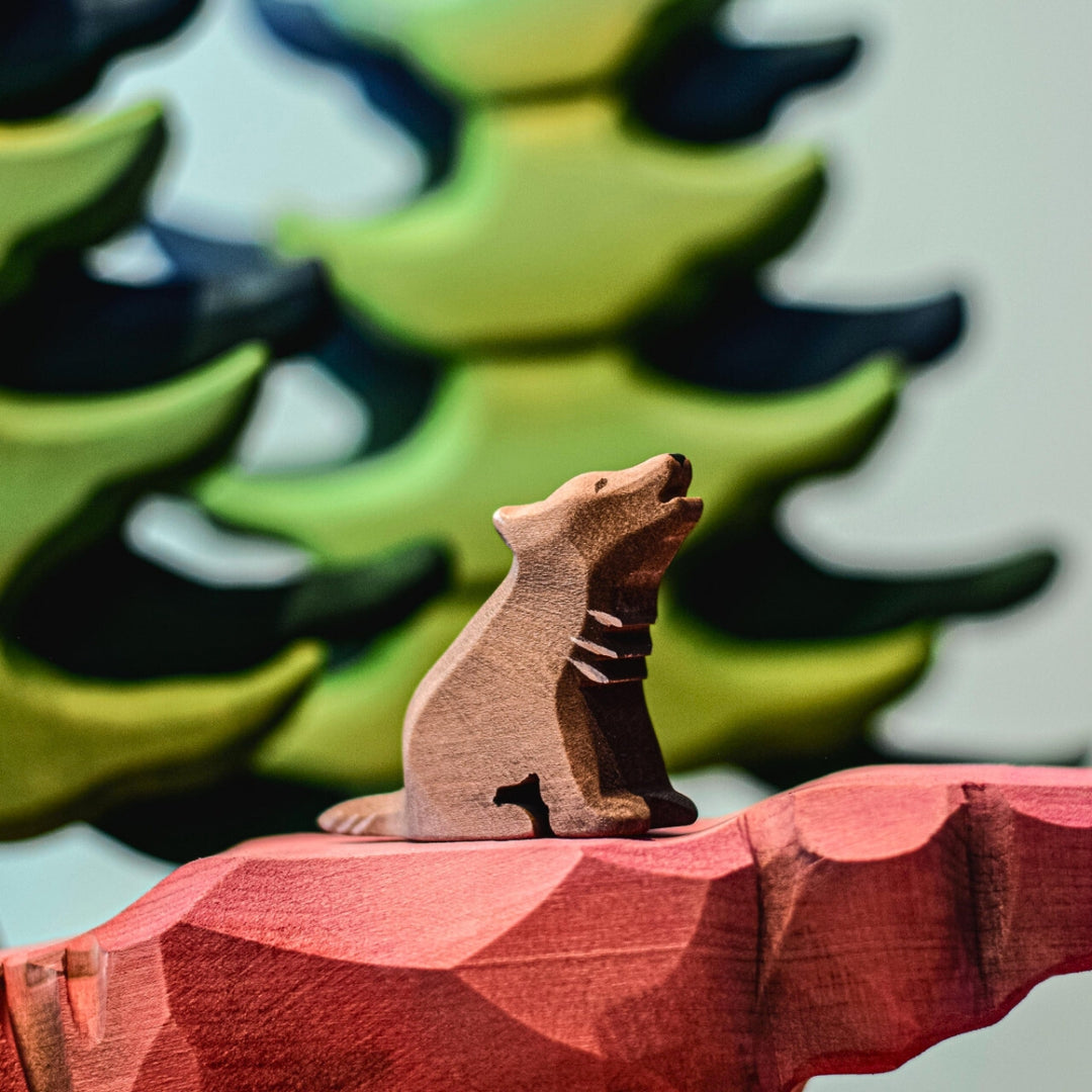 BumbuToys Handcrafted Wooden Animal Wolf Cub Sitting and Howling from Australia in a small-world play setting