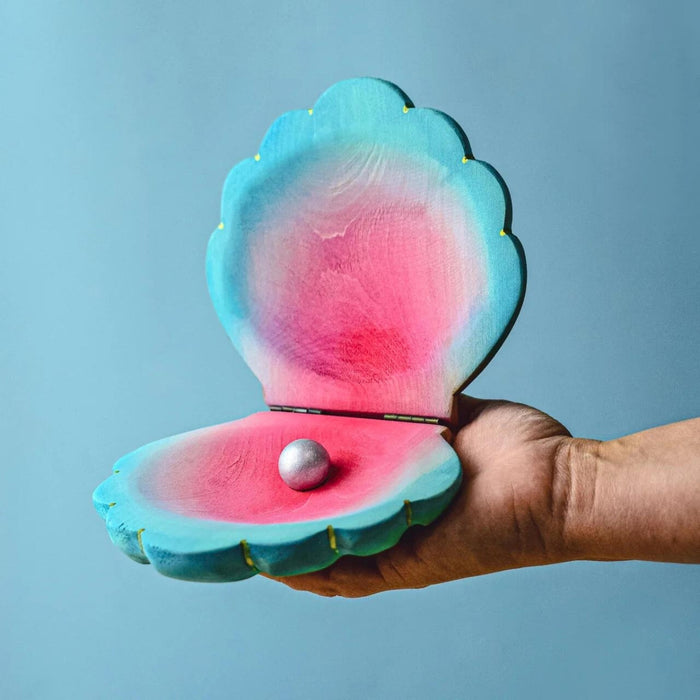 BumbuToys Handcrafted Large Shell with Pearl Wooden Toy from Australia on an adult person's hand