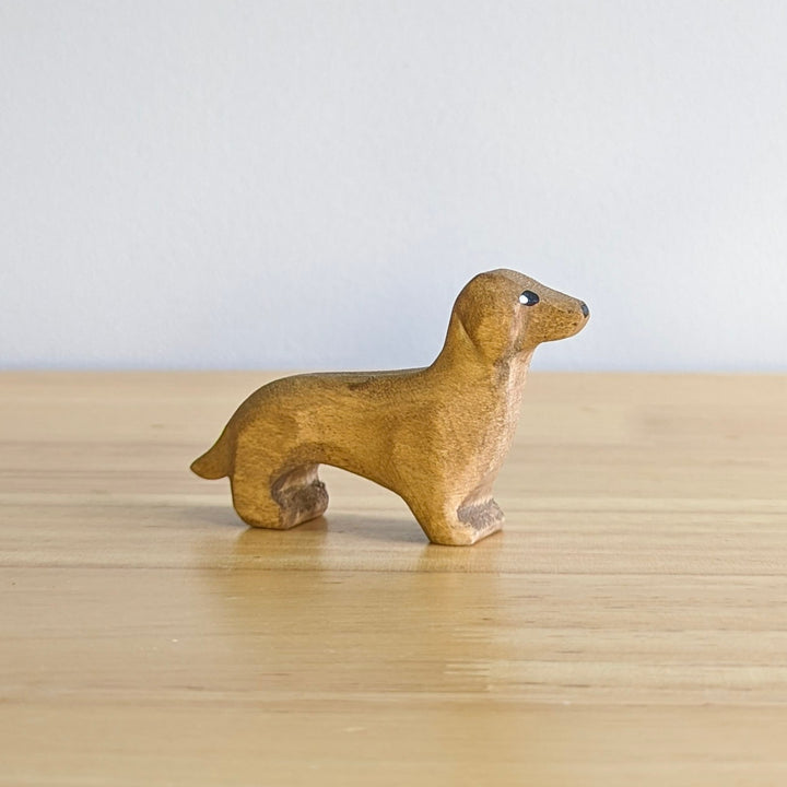 A NOM Handcrafted Wooden miniature Dachshund Sausage Dog model sitting on a table top