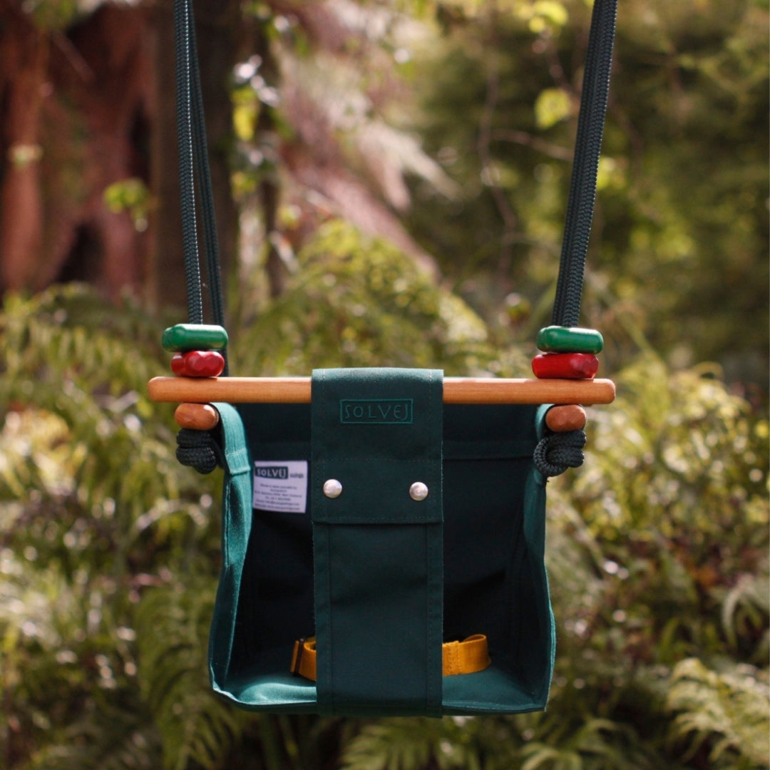 Forest Green SOLVEJ Convertible Baby & Toddler Swing from Australia hung outdoors in a forest