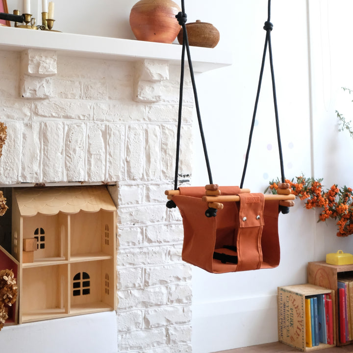 Autumn Rust SOLVEJ Convertible Baby & Toddler Swing hung indoors in a child's play room