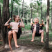 A little girl laughing while swinging outdoors in the woods using SOLVEJ Convertible Baby & Toddler Swing with an older girl swinging on a SOLVEJ Child Swing