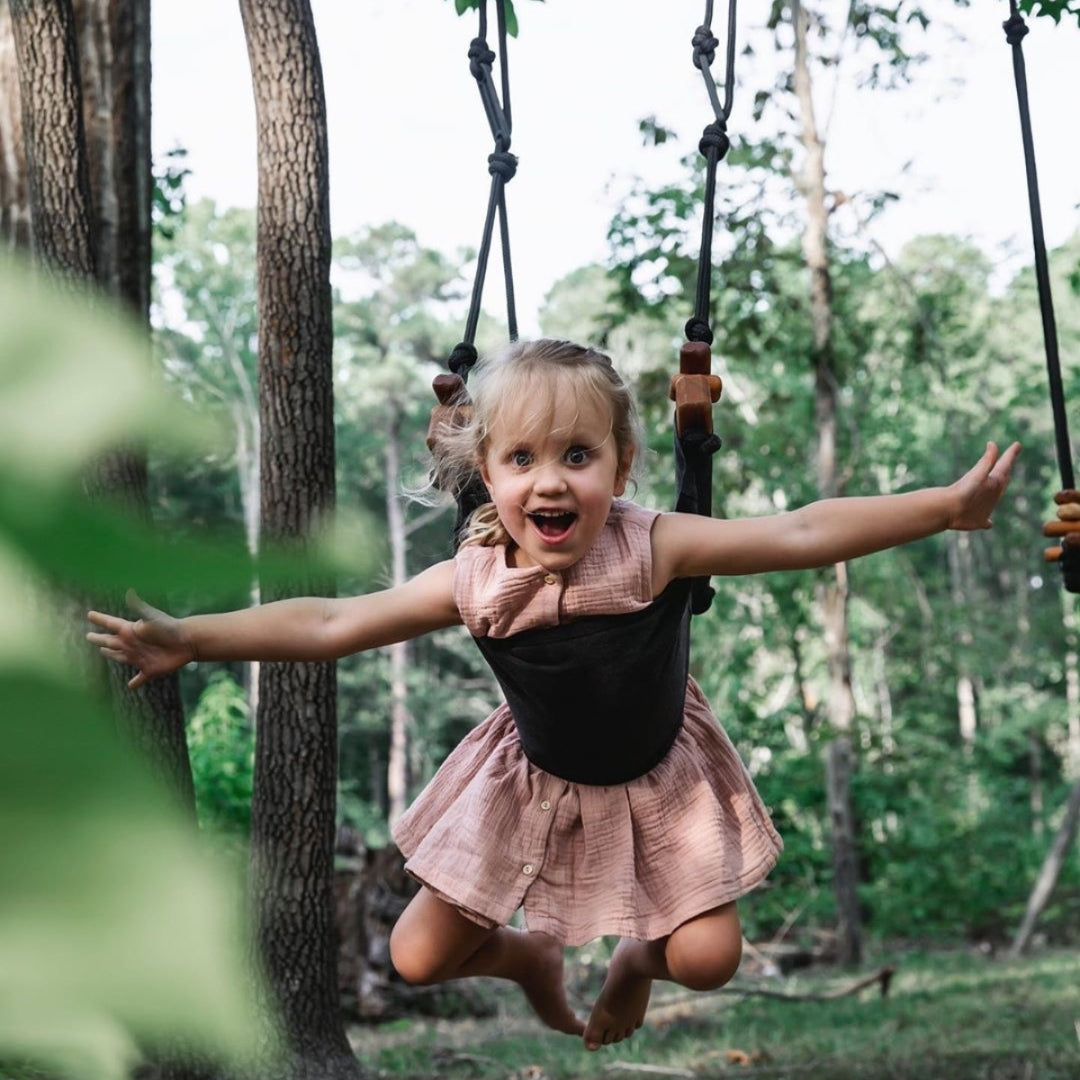 A happy young girl tummy swinging outdoors in the woods using SOLVEJ Child Swing in Slate Grey Colour from Australia